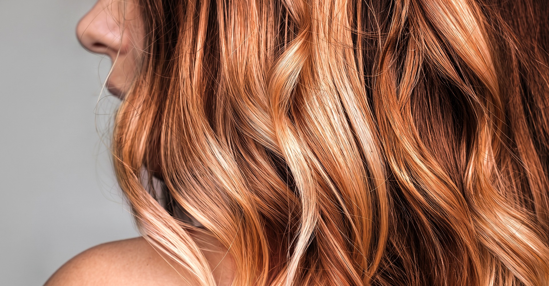 Immagine di una ragazza con capelli mossi, biondi con dei riflessi rossi. Lo sguardo è rivolto verso sinistra